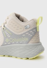 Adidași impermeabili Columbia bej și gri, cu partea superioară din plasă, talpă texturată și maner galben, pe fundal alb.