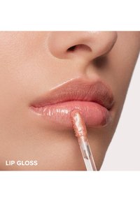 Lippenbalsam wird auf volle, glänzende Lippen aufgetragen. Der Gloss erscheint transparent und schimmernd, mit einer sanften Pfirsichfarbe und einem plastischen Applikator.