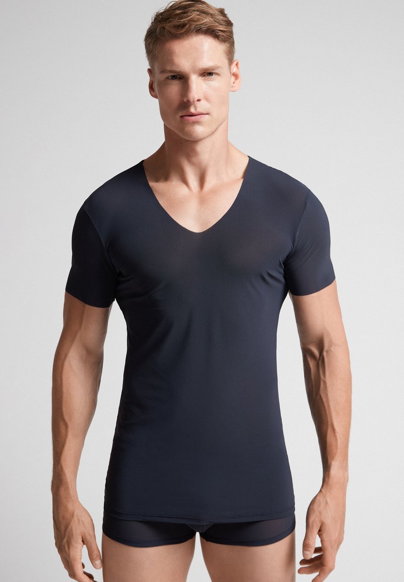 Camiseta de cuello en V de manga corta en azul marino, confeccionada en una tela suave y elástica, con un diseño ajustado, combinada con pantalones cortos a juego.