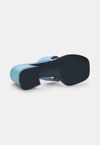 Blue heeled sandal with a smooth finish, wide ankle straps, and a square heel. The sole is black with a textured underside for grip.