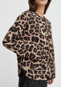 Giacca in stampa leopardata con una combinazione di colori beige e nera, chiusura con bottoni, vestibilità rilassata e tasche laterali. Realizzata in tessuto morbido.