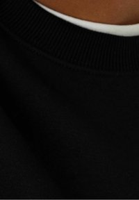 Sudadera negra con un cuello acanalado, que presenta una textura suave y una superficie lisa. La imagen se centra en el área del cuello y los detalles de la tela.