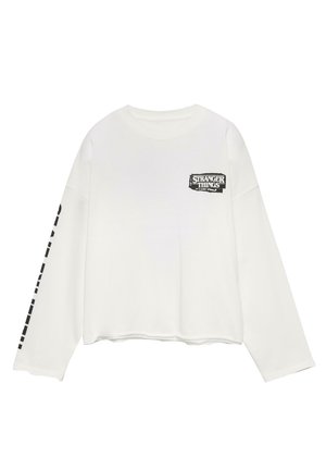 Witte katoenen langemouwen shirt met een zwart "Stranger Things" logo op de borst en grafisch ontwerp langs de linker mouw.