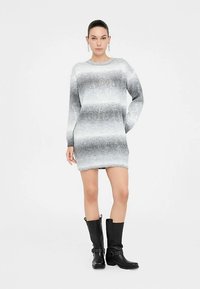 Robe-pull oversize gris et blanche en maille, manches longues, poignets côtelés et coupe décontractée, avec un dégradé de couleur progressif.