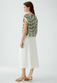 Gebreide top met groen-wit bladerenpatroon, korte mouwen; gecombineerd met een witte A-lijn rok en beige sandalen met een slanke hak.