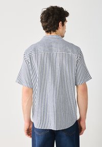 Kurzarmhemd mit blau-weißem gestreiftem Muster, mit Kragen, lockerem Schnitt, geradem Saum und sichtbaren Nähten.