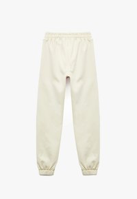 Cremefarvede sweatpants lavet af blødt stof med en elastisk talje og snævre cuffe ved anklerne. Ingen synlige mærker eller mønstre.