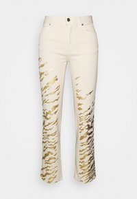 Jeans color crema con un patrón de rayas de tigre metálicas doradas, que cuentan con cinco bolsillos, cierre de botón y una cintura ajustada. Diseño de pierna acampanada.