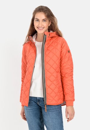 Gepolsterte orange Jacke mit Kapuze, ausgestattet mit einem Reißverschluss, kontrastierenden Reißverschluss und gerippten Bündchen. Getragen über einem weißen Oberteil und blauen Jeans.