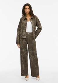 Chaqueta de estampado de serpiente marrón y pantalones de pierna ancha a juego, hechos de un tejido suave. La chaqueta tiene botones y un cuello puntiagudo; ambas piezas tienen un acabado texturizado.