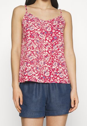 Camisola rosa a maniche corte con motivo floreale e scollatura a V, caratterizzata da fiori blu e bianchi. Abbinata a pantaloni corti in denim scuro.