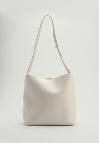 Hobo tas, glad beige leer, gebogen bovenkant, enkele verstelbare schouderband, minimalistisch ontwerp, geen zichtbare hardware, zachte textuur.