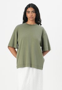 Olivengroen oversized t-shirt van zacht katoen, met korte mouwen, een ronde halslijn en een ontspannen pasvorm met zichtbare stikseldetails.