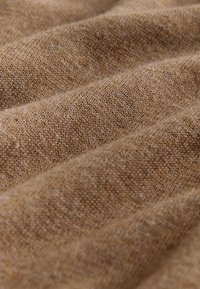Tan woven fabric with a textured surface, featuring subtle horizontal stripes. The material is soft and slightly fuzzy, creating a warm appearance.