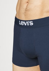 Boxers bleu marine en tissu doux, avec un logo Levi's blanc sur une ceinture élastique, conception ajustée et texture lisse.