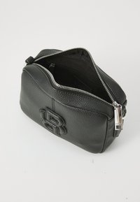 Black leather handbag with a pebbled texture, zip closure, and embossed logo detail. Interior has a fabric lining and an additional zip pocket.