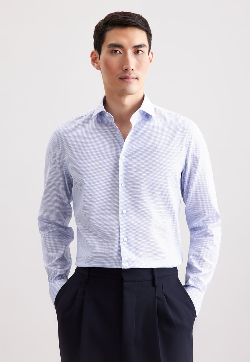 Camicia azzurro chiaro con un motivo sottile, colletto button-down, maniche lunghe e una texture liscia, abbinata a pantaloni scuri.