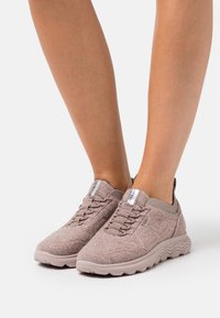 Baskets décontractées rose clair en tissu texturé. Elles disposent de lacets élastiques, d'une semelle rembourrée et d'une languette à l'arrière pour un enfilage facile.