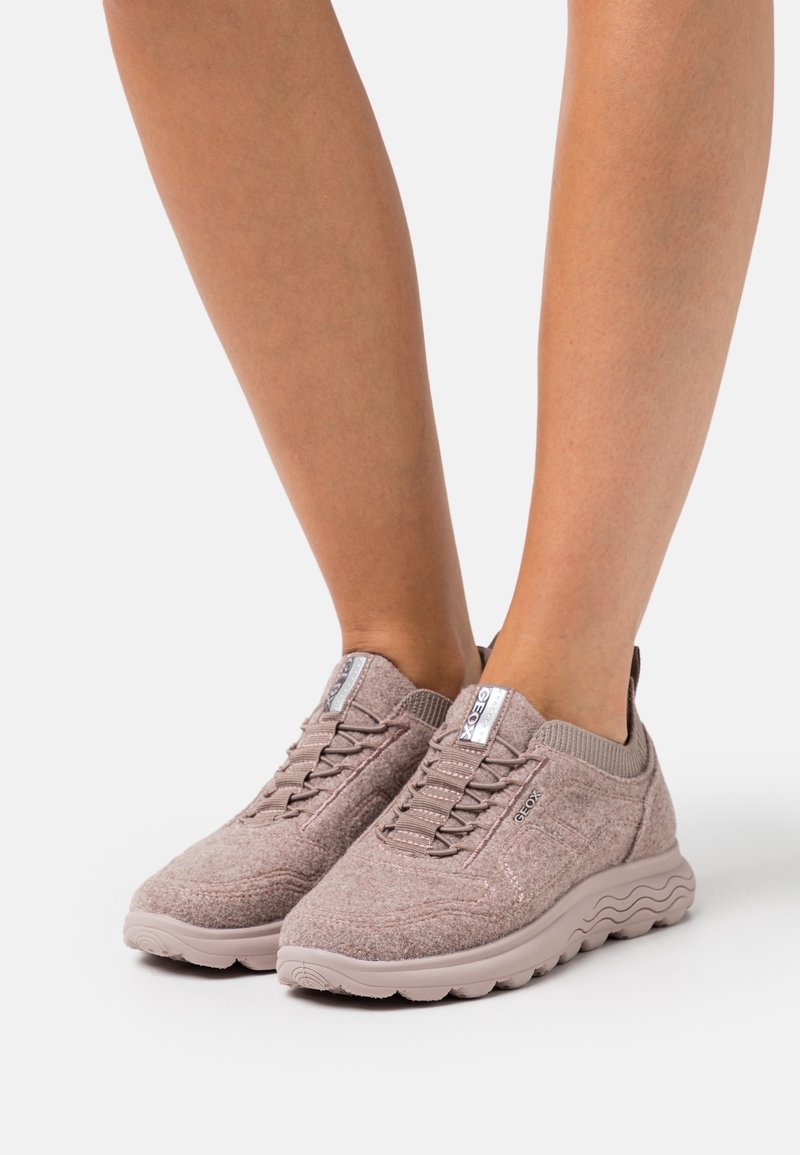 Baskets décontractées rose clair en tissu texturé. Elles disposent de lacets élastiques, d'une semelle rembourrée et d'une languette à l'arrière pour un enfilage facile.