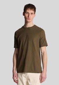 T-shirt marrone a maniche corte con colletto rotondo, realizzato in tessuto morbido, con un discreto etichetta logo sul lato inferiore.