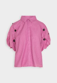 Camicia rosa, con texture, colletto, maniche a sbuffo corte e dettagli floreali neri sulle spalle. Design con bottoni sul davanti.