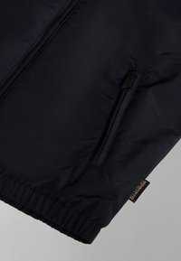 Navy puffer jacket featuring a zippered pocket, elastic cuffs, and a logo tag. Smooth, lightweight material with a slight sheen.