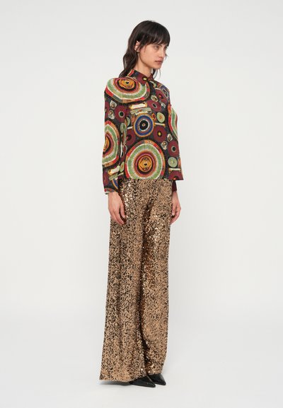 Multicolor knoopshirt met ronde patronen, gecombineerd met hoge taille, wijde gouden paillettenbroeken. Glad, glanzend textuur overal.