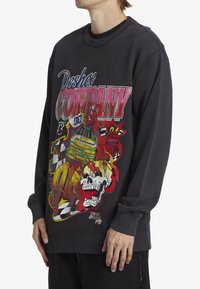 Black sweatshirt featuring vibrant graphic prints, including a skull and racing elements, with ribbed neckline and cuffs.