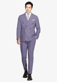 Traje de lana morado a medida con chaqueta de doble botonadura, solapas con muesca y dos bolsillos delanteros. Acompañado de una camisa clara y una corbata con estampado.