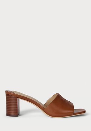 Mule en cuir marron à bout ouvert avec une large lanière, dotée d'un talon bloc avec une texture rainurée. La semelle est lisse et plate.