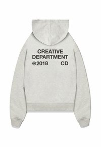 Grå huvtröja med en kortad design. Har kraftig tryckt text på baksidan: "KREATIVT AVDELNING 2018 CD." Mjuk textur.