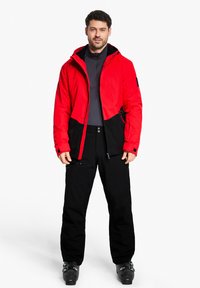 Rote und schwarze isolierte Jacke mit Kapuze, Reißverschluss vorne, kontrastierenden Einsätzen und schwarzen Hosen. Glattes Gewebe mit Taschen und Reißverschlüssen.