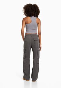 Šedý žebrovaný crop top a šedé cargo kalhoty s několika kapsami. Kalhoty mají uvolněný střih a rovný design nohavic.