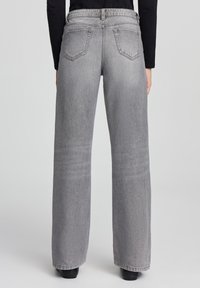 Jeans a gamba larga grigi con tessuto in denim, caratterizzati da un alto girovita, due tasche posteriori e una leggera scoloritura lungo le gambe. Texture liscia.