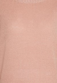 Pull en tricot rose doux, avec une texture côtelée, un col rond et une coupe décontractée. Parfait pour le superposition ou une tenue décontractée.