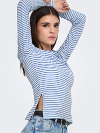 Langærmet, stribet top i lyseblå og hvid med sidesplitter ved kanten. Båret med højtaljede denimshorts og et sort bælte.