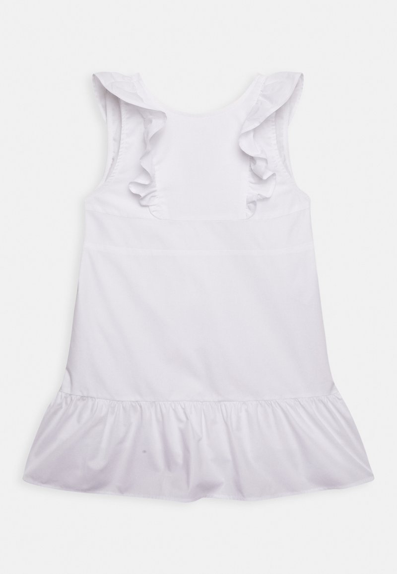 Robe sans manches blanche pour tout-petits avec des bretelles à volants et un ourlet froncé, posée à plat sur un fond blanc.