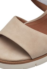 Sandale en daim beige avec une large sangle, semelle intérieure marron et semelle plateforme de couleur claire avec des accents en liège.
