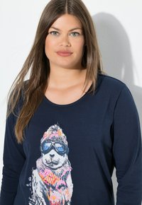 Marineblaues Langarmshirt mit einem Grafikdruck eines Cartoon-Tiers, das eine Sonnenbrille und einen bunten Schal trägt, aus leichtem Material gefertigt.