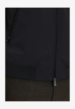 Marineblaue Windjacke mit glatter Textur, Reißverschluss und elastischen Bündchen; verfügt über einen dezenten Glanz und minimalistisches Design.