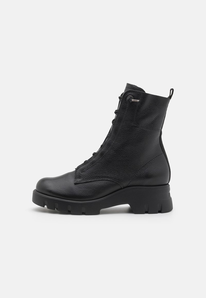 Bottine noire en cuir avec lacets à l'avant, semelle épaisse et languette à l'arrière, vue de profil droit sur fond blanc.