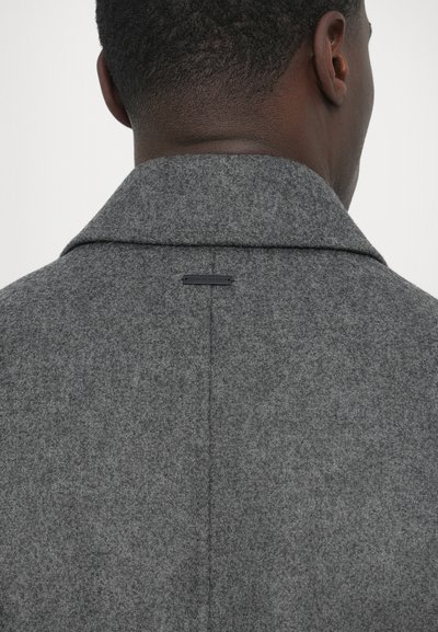 Γκρι μάλλινο παλτό με γιακά με εγκοπές, μεσαία υφή και μικρή ετικέτα στο πίσω μέρος. Χωρίς ορατά κουμπώματα ή διακοσμήσεις.