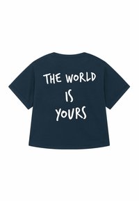 T-shirt en coton bleu marine avec une coupe loose. Le texte au dos indique "LE MONDE EST À VOUS" en lettres blanches en gras. Manches courtes, col rond.