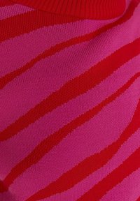 Gros plan sur un tissu tricoté rayé rose et rouge avec un col côtelé.