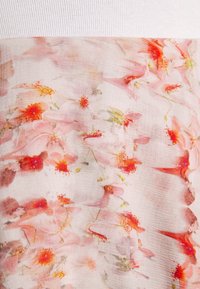Tissu léger arborant un motif floral dans des teintes de rose et d'orange, avec une texture lisse et une section supérieure en côte blanche solide.