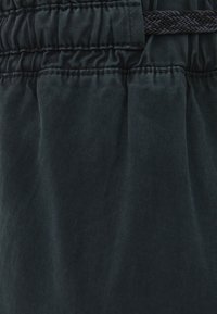 Černé, lehké kalhoty s texturovaným povrchem, vybavené elastickým páskem a pletenou šňůrkou, které zdobí jemné vertikální pruhy.