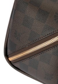 Bruine leren tas met een gestructureerd oppervlak, voorzien van een gouden ritssluiting en een geruit patroon. Het ontwerp bevat zowel gladde als gestructureerde delen.