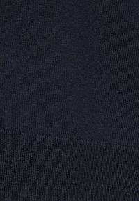 Tmavě námořnická pletenina s hladkou texturou. Rovnoměrný tkaninový vzor a žebrovaný lem podél spodního okraje.