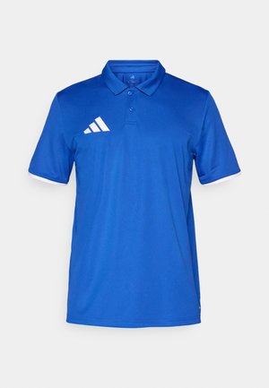 Plava polo majica s ovratnikom, kratkim rukavima i bijelim detaljima. Ima tri bijele pruge na području s logom na lijevoj strani prsa. Izrađena je od teksturiranog materijala.