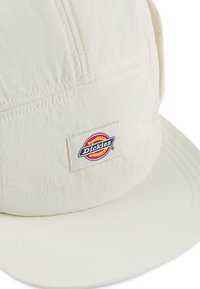Weißer, leichter Hut mit einem strukturierten Schild, texturiertem Stoff und einem rechteckigen Dickies-Logo-Patch auf der Vorderseite.